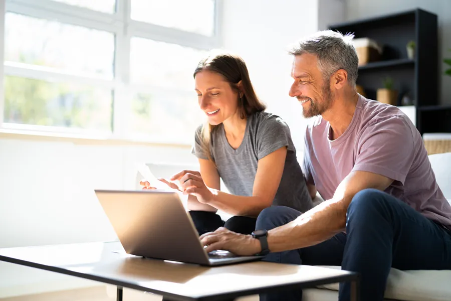 A middle-aged couple applying for financing in their living room on a laptop.