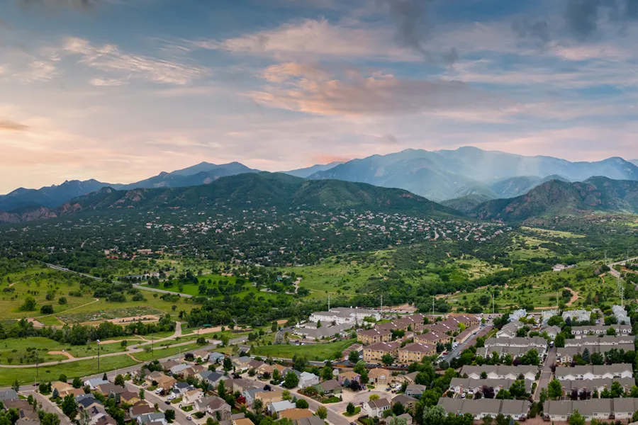 An aerial panoramic photo of Colorado Springs neighborhoods at the foot of the Rocky Mountains.