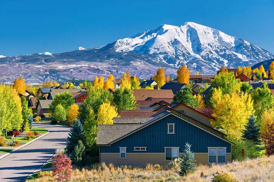 A residential neighborhood in Colorado during the early months of Autumn, with a mountain in the background.