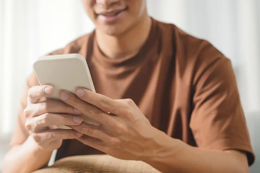 A young man using a smartphone inside his home.